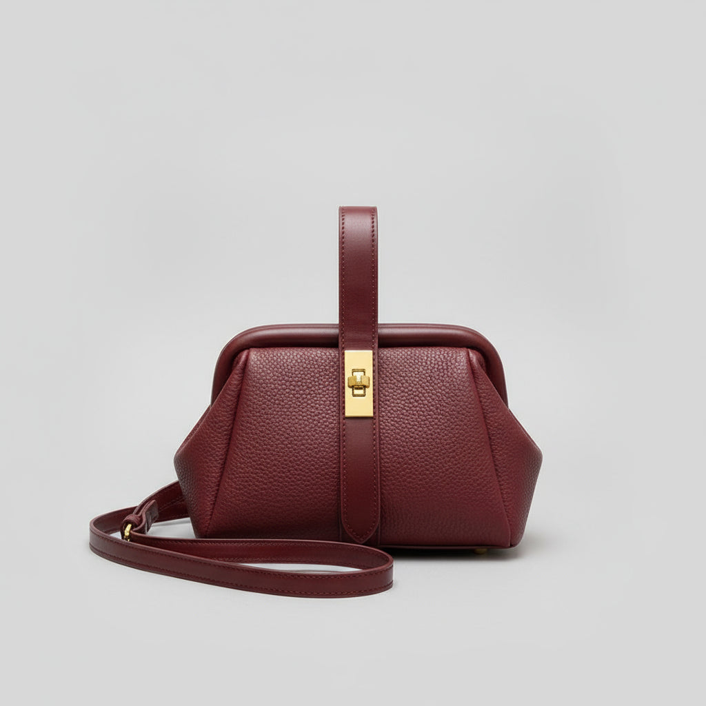 Red handbag with a gold clasp on a table with a cityscape view in the background