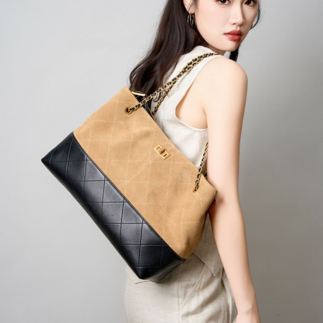Woman holding a quilted beige and black handbag against a plain background