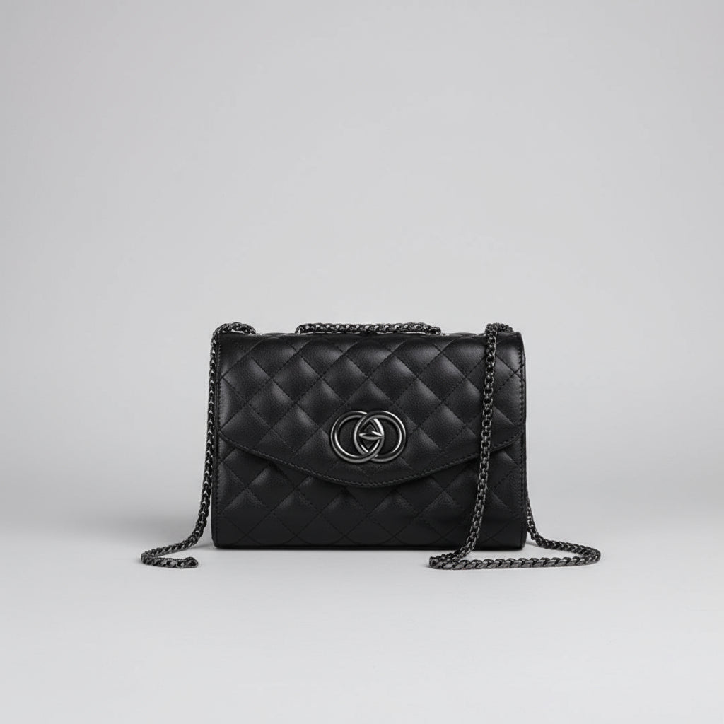 Black quilted handbag with a brand logo held by a hand against a white background