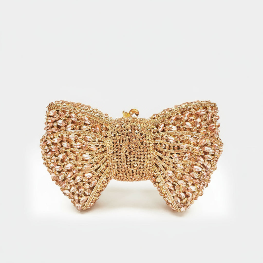 Gold bow-shaped clutch with crystal embellishments on a white background