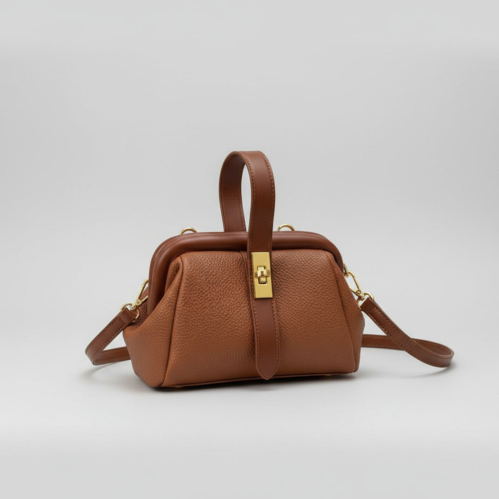 Brown leather handbag held by a hand on a light background