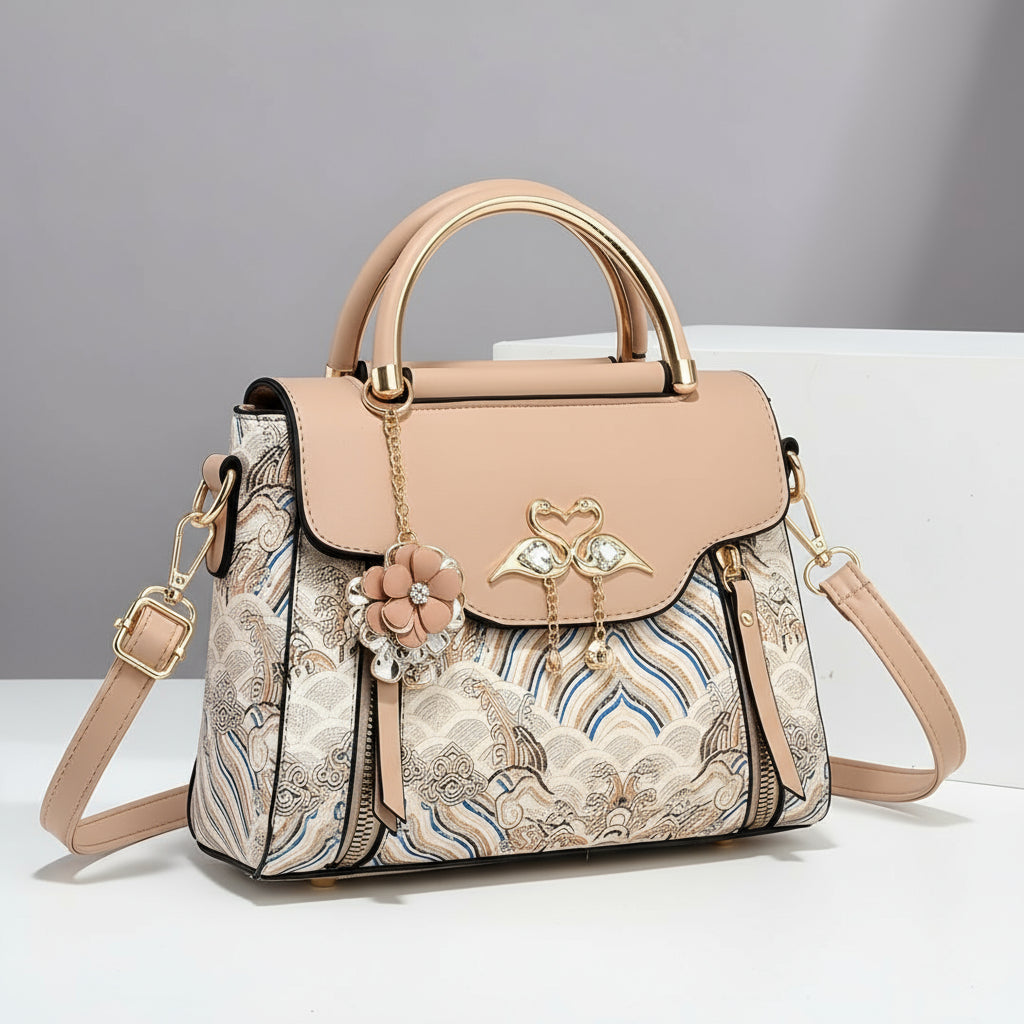 Designer handbag with floral pattern and gold accents on a neutral background