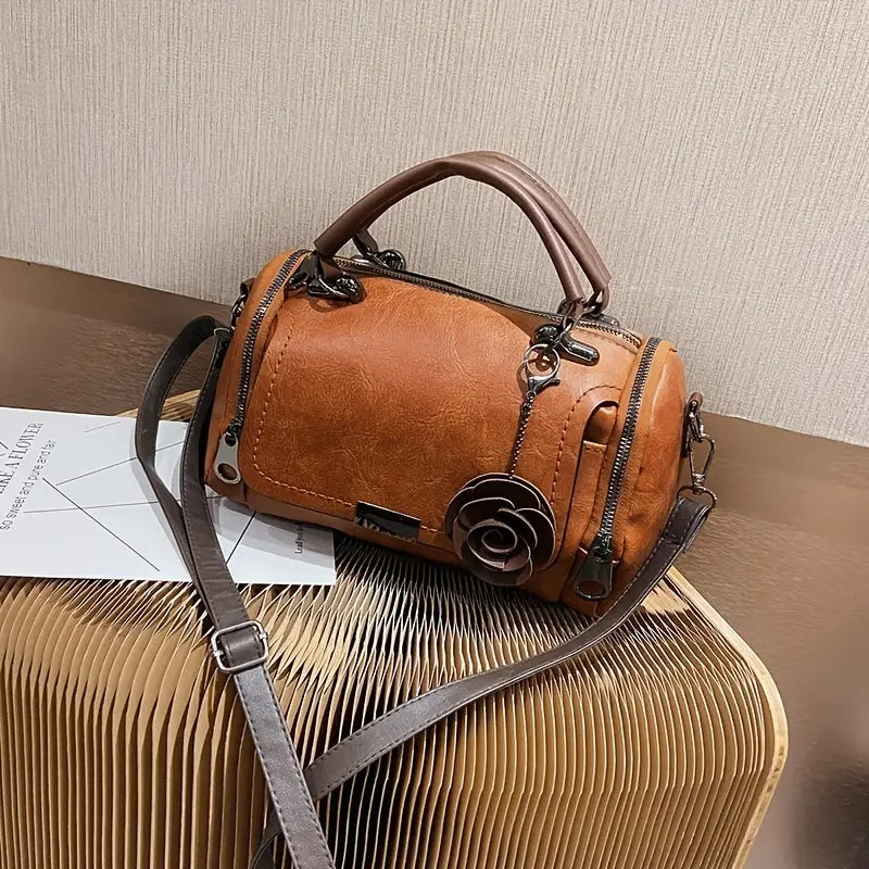 Brown leather handbag with floral detail on a textured surface