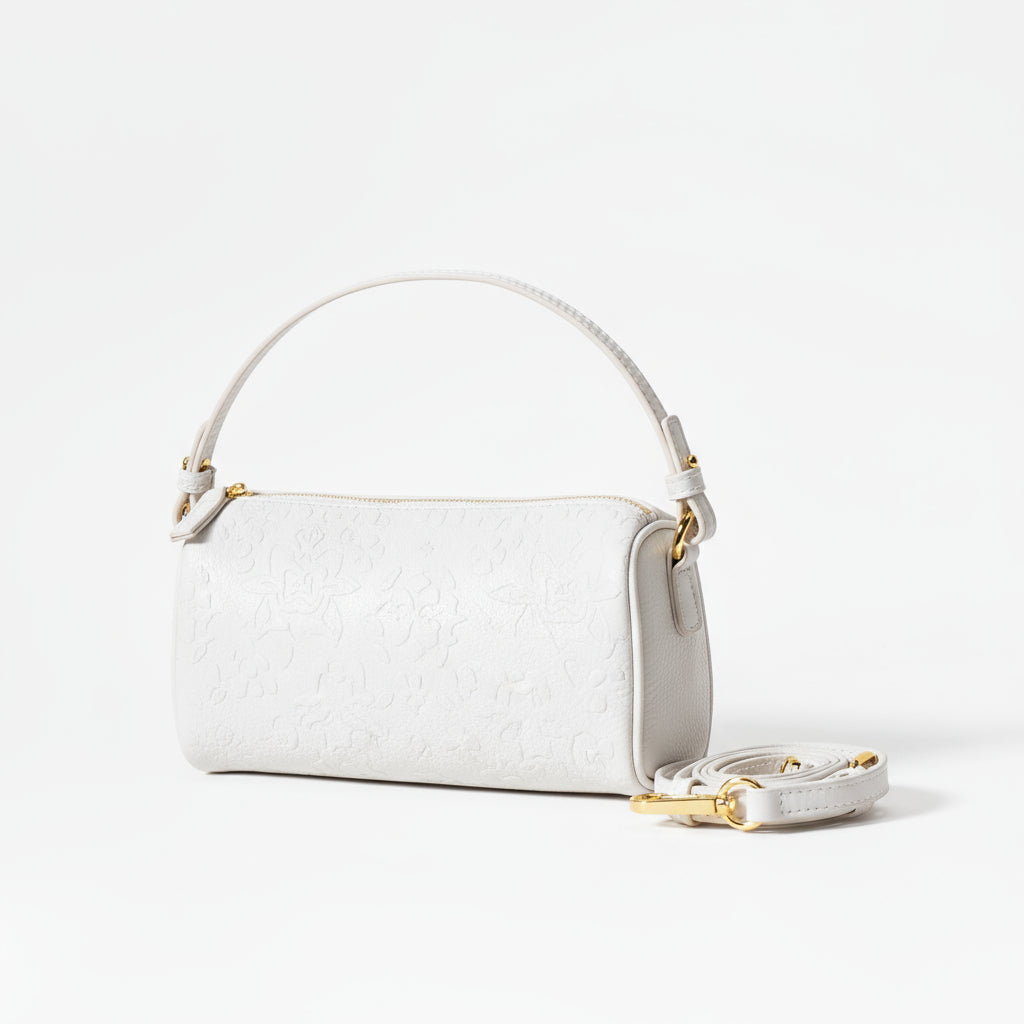 White handbag with gold accents on a beige background