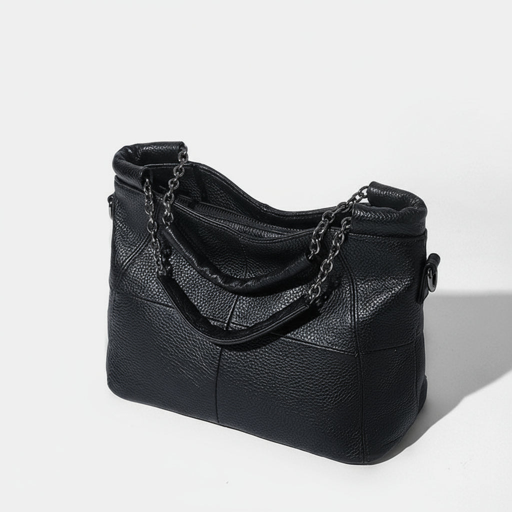Black leather handbag with chain detail on a white background