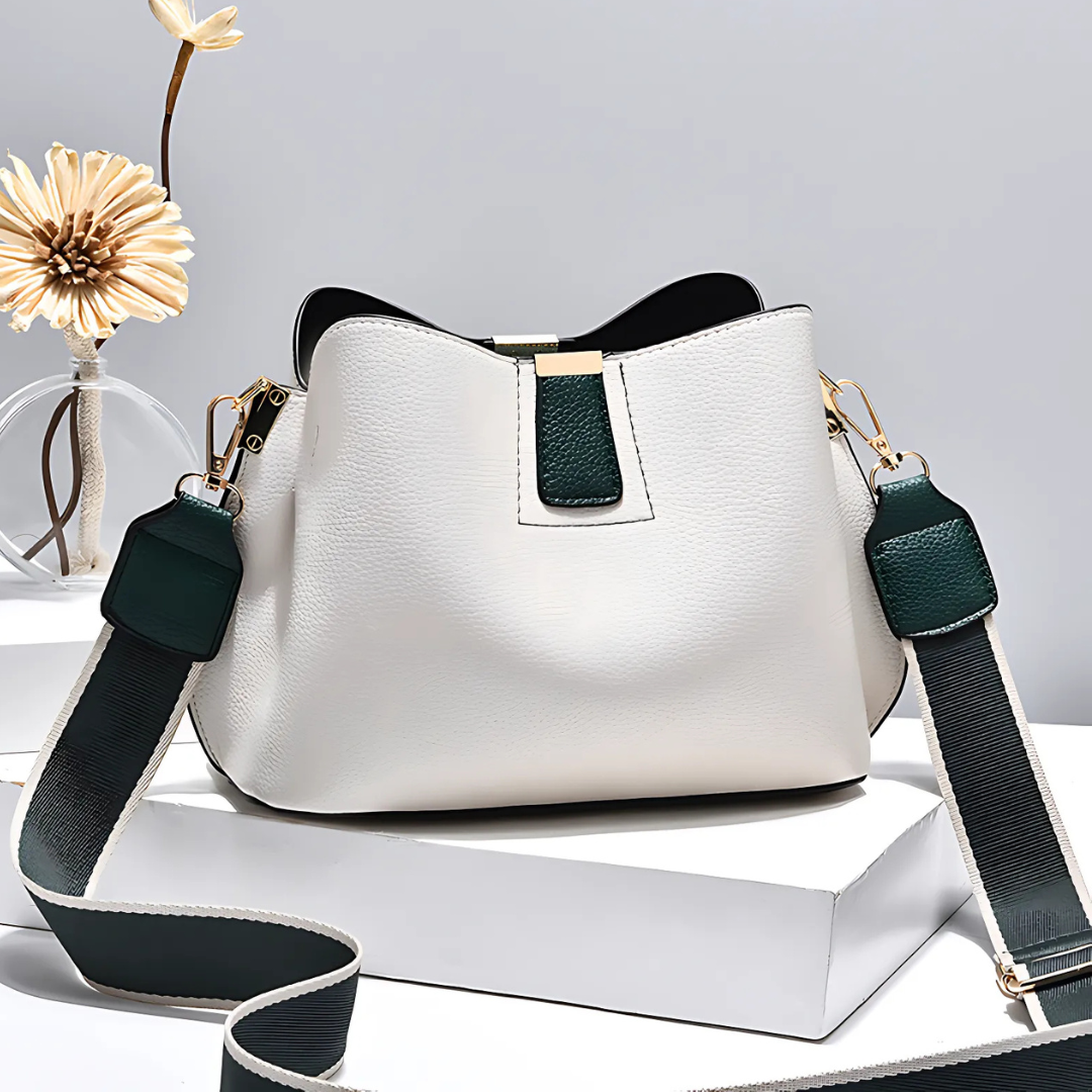 White handbag with green accents on a white surface with a light gray background