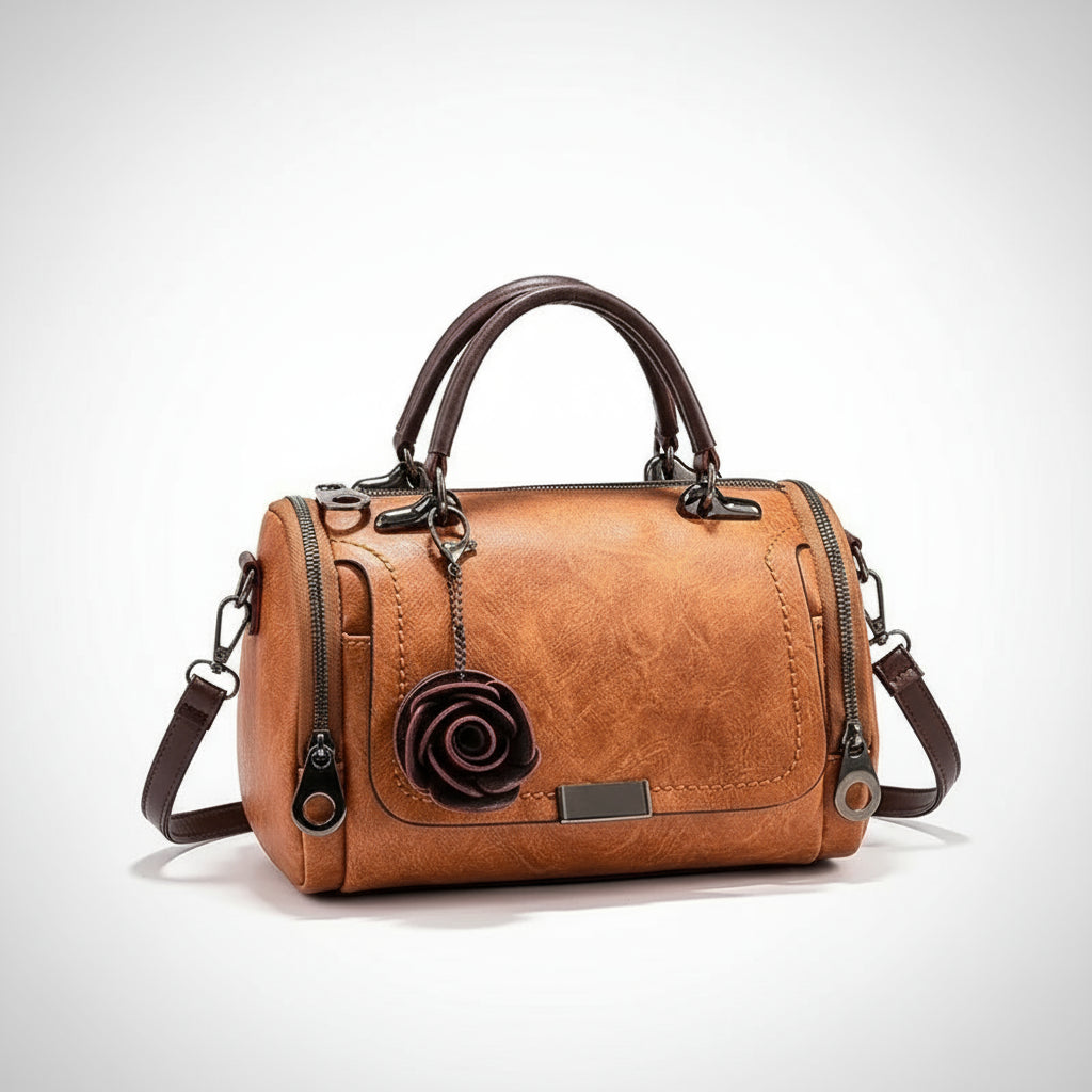 Brown leather handbag with floral detail on a wooden surface