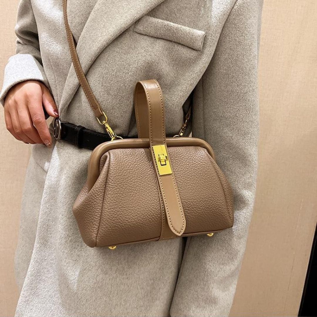 Brown handbag with gold accents worn over a gray coat