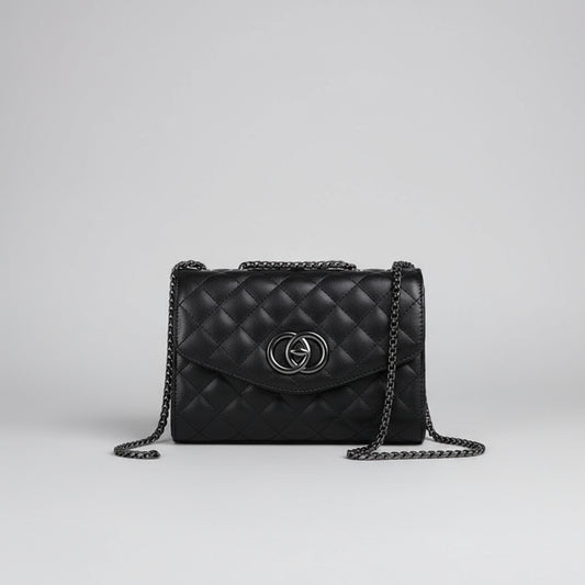 Black quilted handbag with a brand logo held by a hand against a white background
