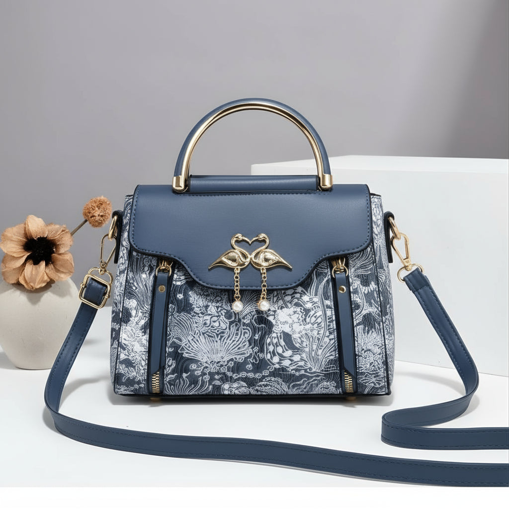 Blue handbag with floral pattern and gold accents on a white background