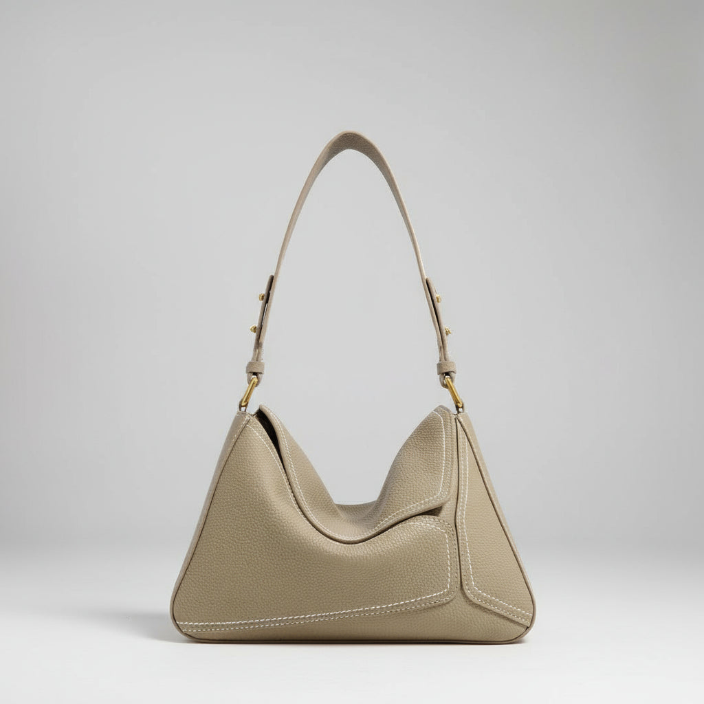 Beige handbag on a white surface with a neutral background