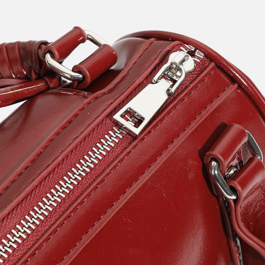 Close-up of a red handbag with a silver zipper and handle.