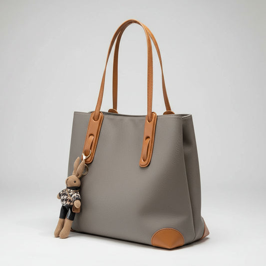 Gray handbag with brown handles and trim on a light surface.