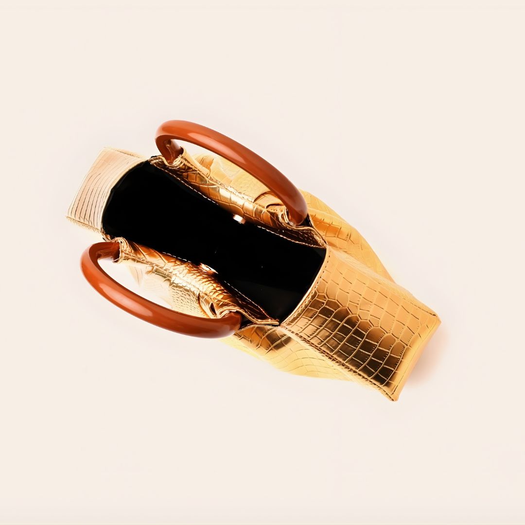 Gold handbag with brown handles on a light beige background