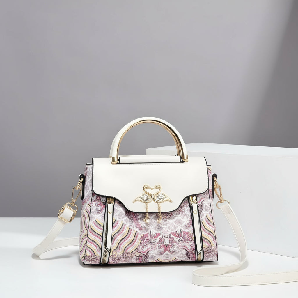 Designer handbag with floral pattern and gold accents on a gray background