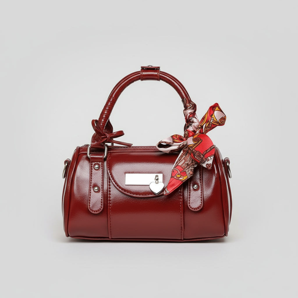 Red handbag with a matching scarf held by a person against a beige background