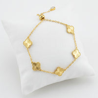 Gold bracelet with clover-shaped links on a white background