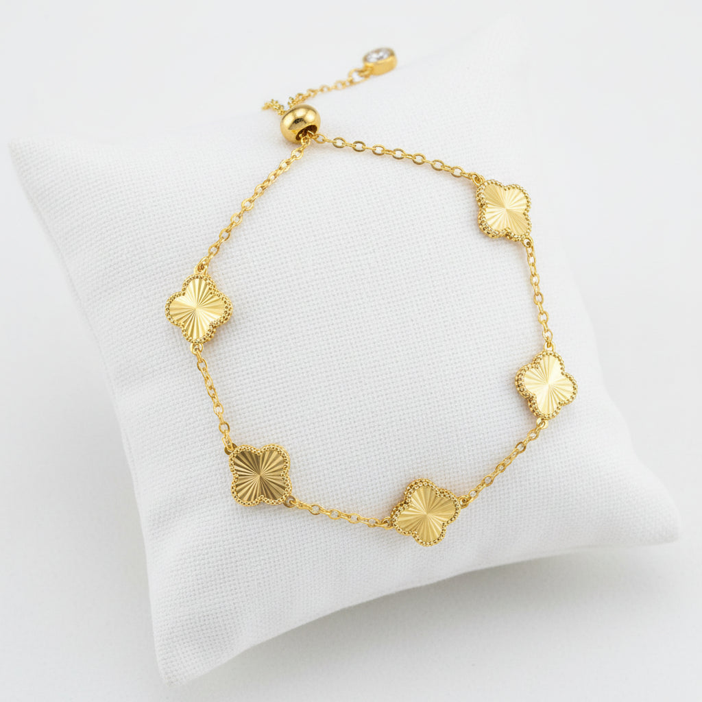 Gold bracelet with clover-shaped links on a white background