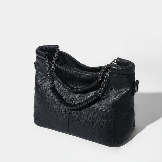 Black leather handbag with chain detail on a white background