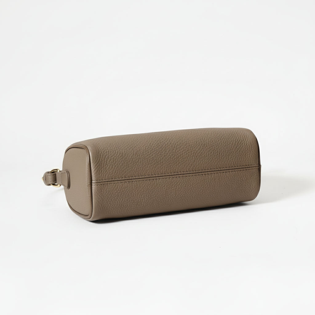 Brown leather cylindrical bag on a beige background