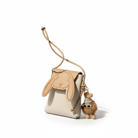 Handbag with bunny ears design and a plush toy keychain on a neutral background