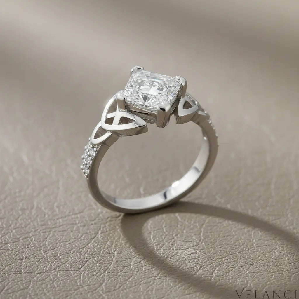 Silver ring with a large diamond and smaller diamonds on the band against a white background