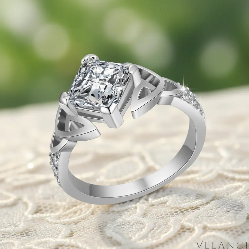 Silver ring with a large diamond and smaller diamonds on the band against a white background