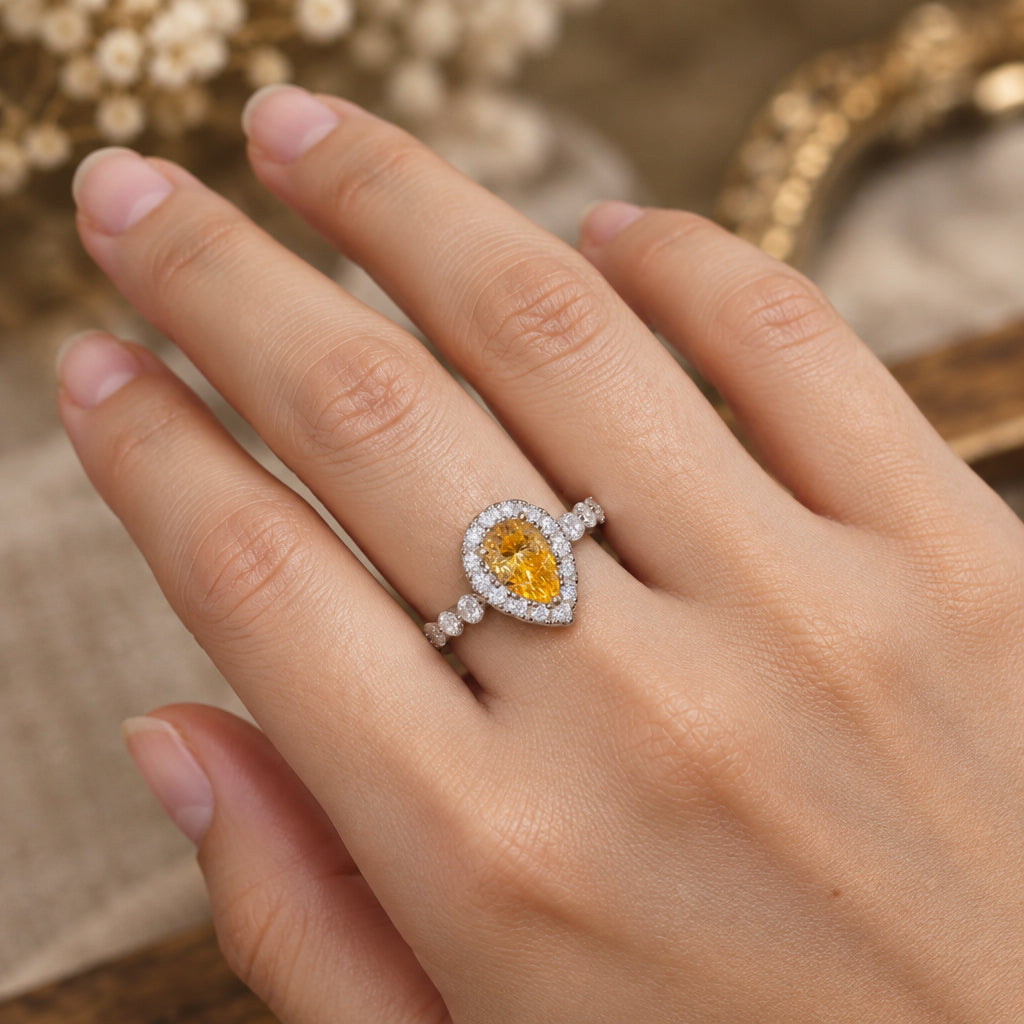 Teardrop-shaped gemstone ring on a finger with a blurred background