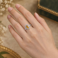 Teardrop-shaped gemstone ring on a finger with a blurred background