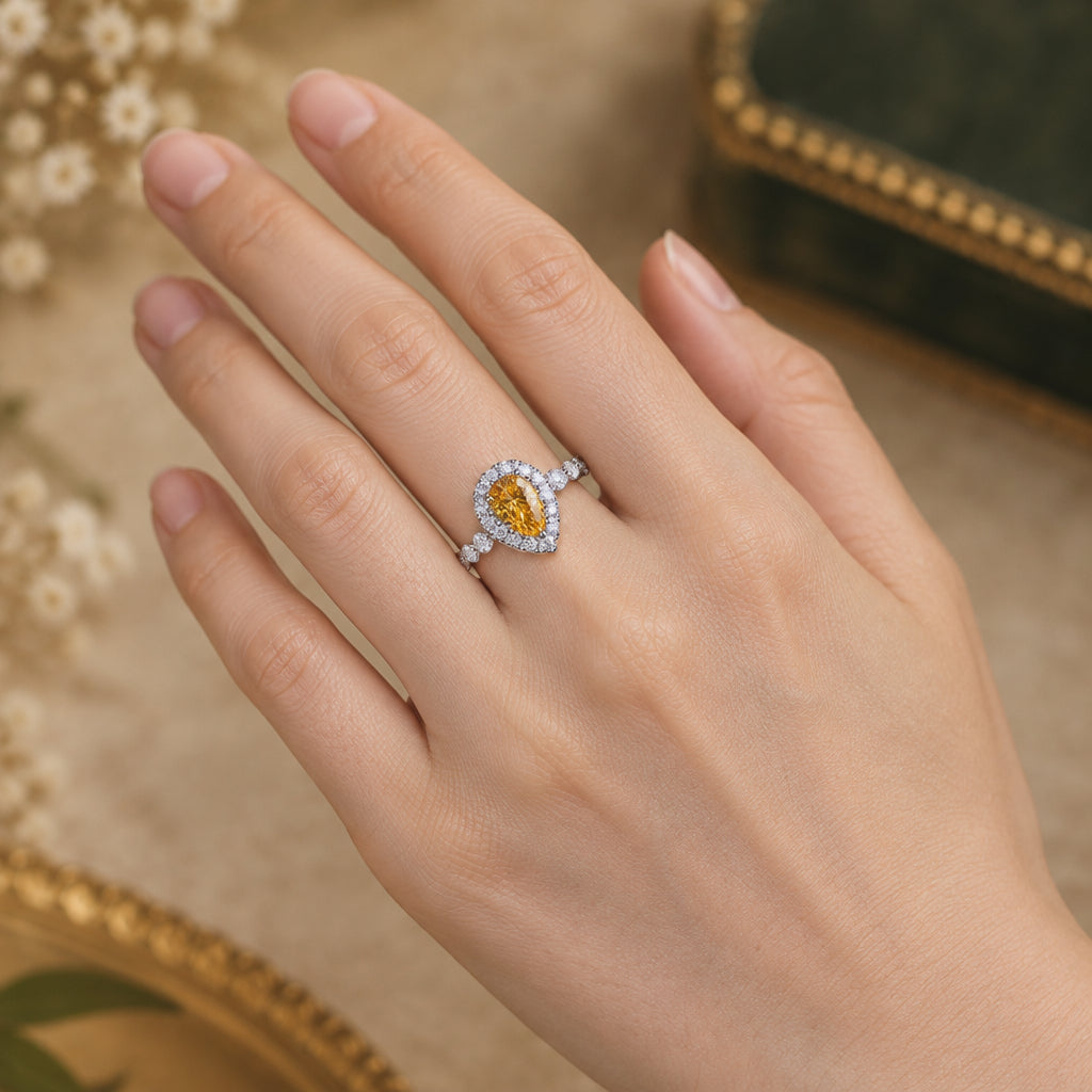 Teardrop-shaped gemstone ring on a finger with a blurred background