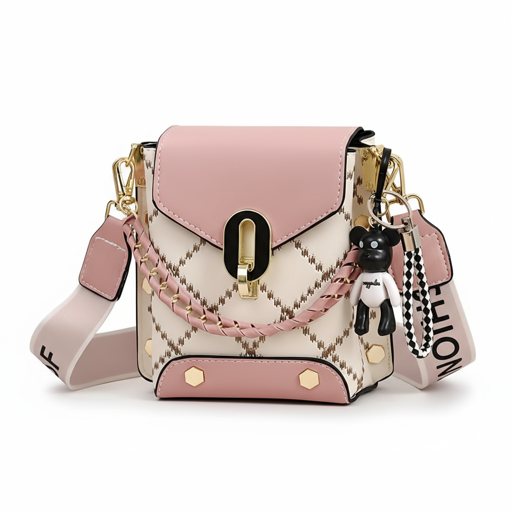 Pink and white handbag with decorative strap and keychain on a wooden surface