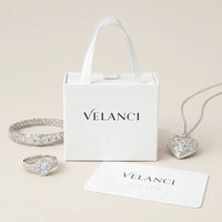 Silver jewelry set including a necklace, ring, and bracelet with a Velanci branded box on a white background.