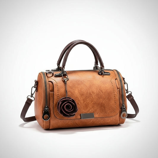 Brown leather handbag with floral detail on a wooden surface