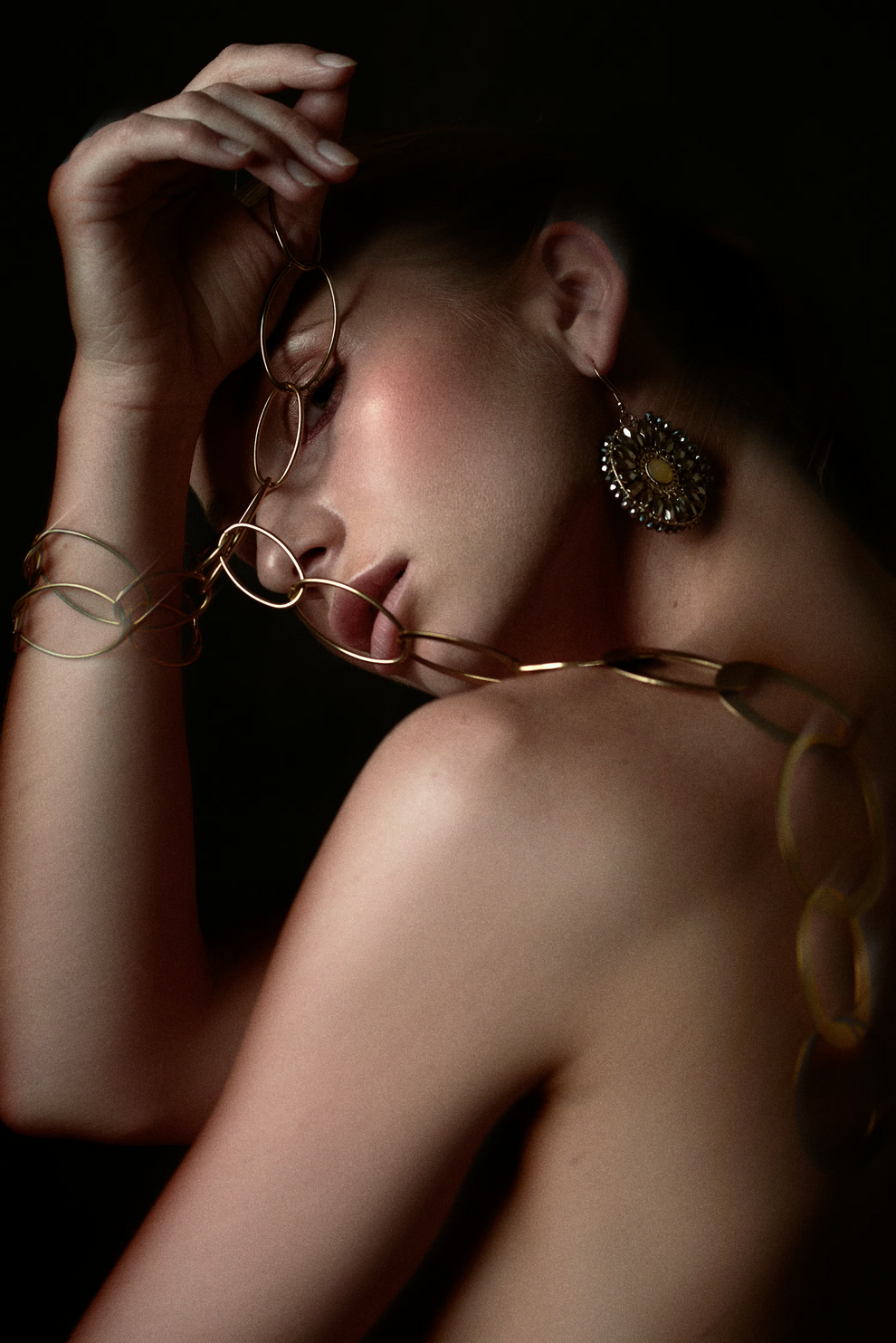Woman wearing gold jewelry against a dark background
