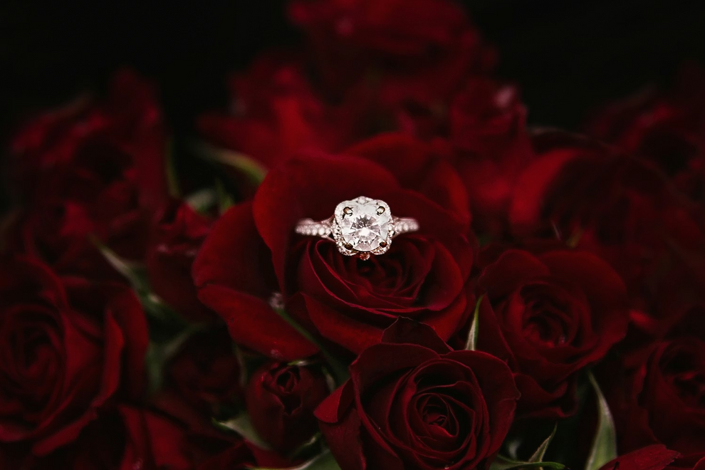 Diamond ring on a bouquet of red roses against a dark background