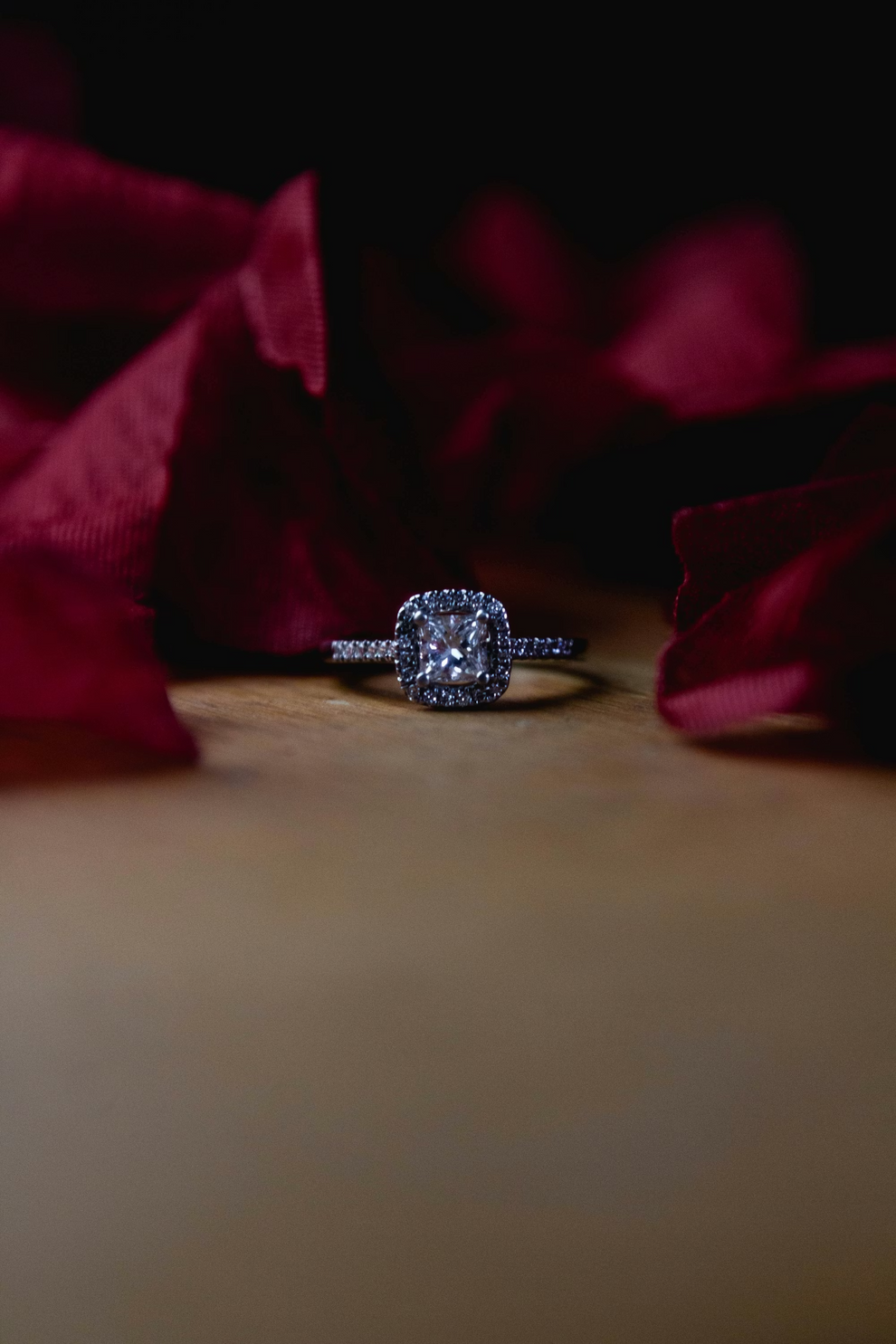 Diamond ring on a wooden surface with red fabric in the background