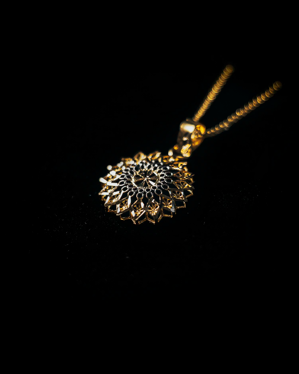Gold necklace with a intricate pendant on a black background